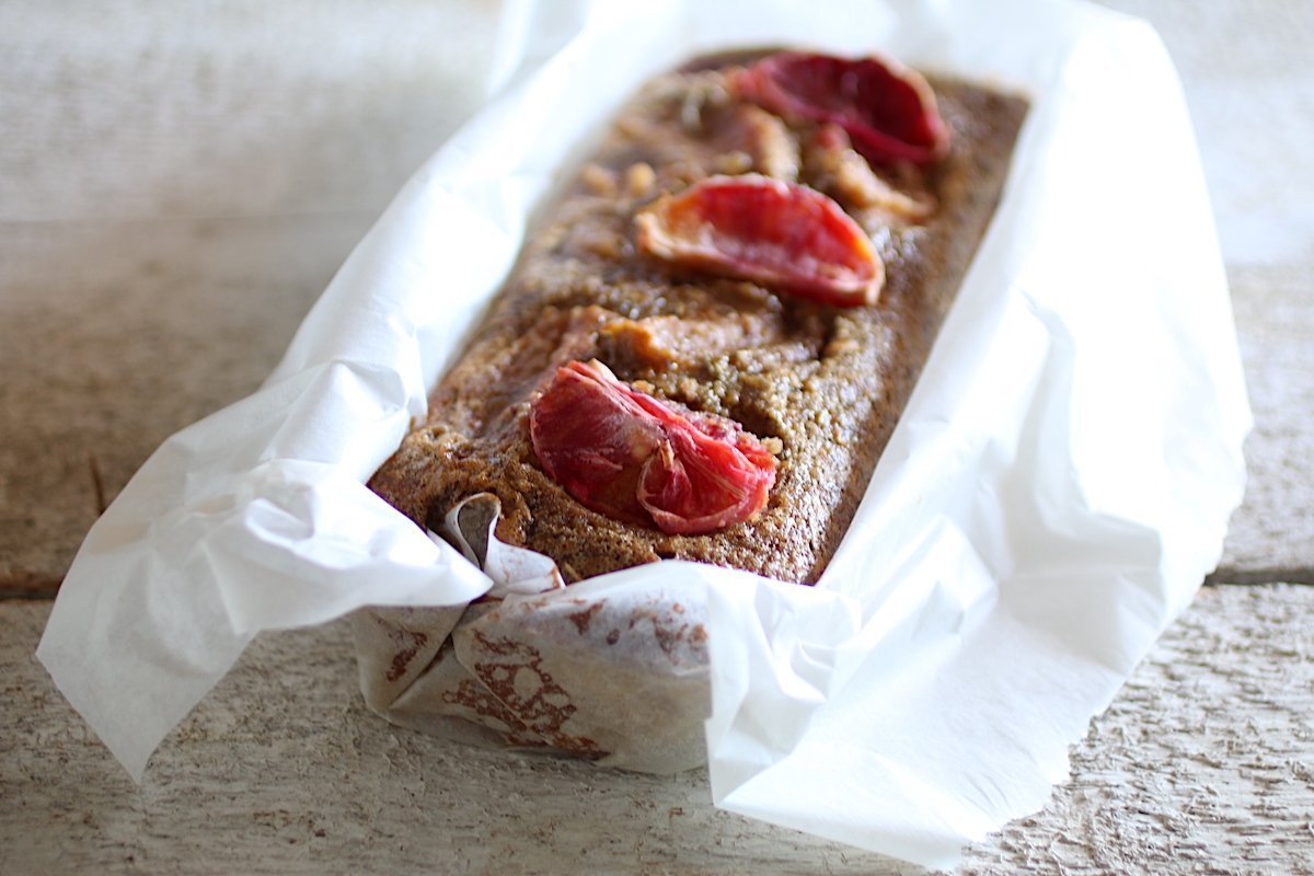 pandolce alle mandorle e arance rosse avvolto nella carta forno sul tavolo bianco