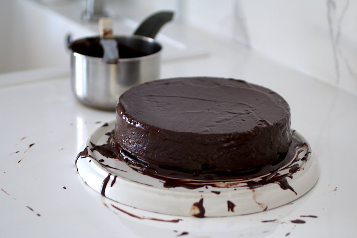 La torta al cioccolato appena decorata con la glassa su un piatto di rialzo